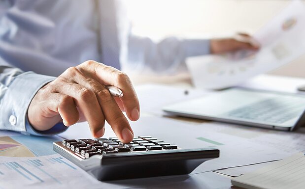 Person kalkuliert am Taschenrechner